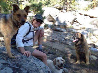 photo of woman hiker with three dogs