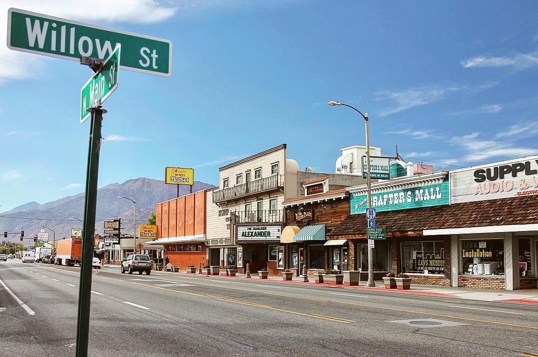 A street view of a quiet town in Bishop, California, with various small shops and a Willow St street sign in the foreground, nestled against the backdrop of the Eastern Sierra. visit bishop