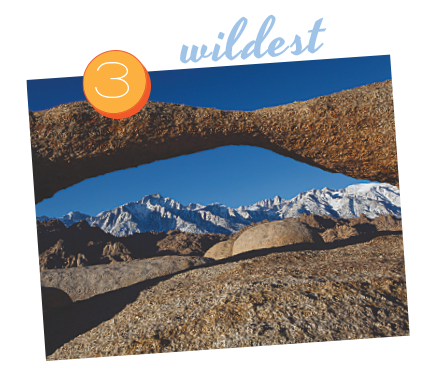 Rocky arch framing a distant snow-capped mountain range under a clear blue sky in Bishop, California, labeled "3 wildest". visit bishop