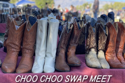 Various cowboy boots displayed on a table at an outdoor market with the text "CHOO CHOO SWAP MEET" in Bishop, California against the stunning backdrop of the Eastern Sierra. visit bishop