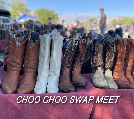 Various cowboy boots displayed on a table at an outdoor market with the text "CHOO CHOO SWAP MEET" in Bishop, California against the stunning backdrop of the Eastern Sierra. visit bishop