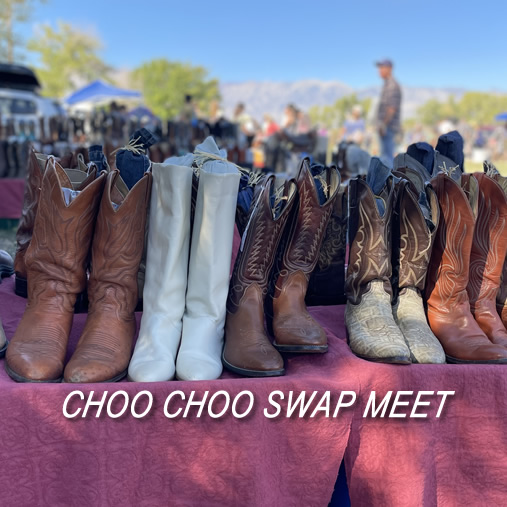 Various cowboy boots displayed on a table at an outdoor market with the text "CHOO CHOO SWAP MEET" in Bishop, California against the stunning backdrop of the Eastern Sierra. visit bishop