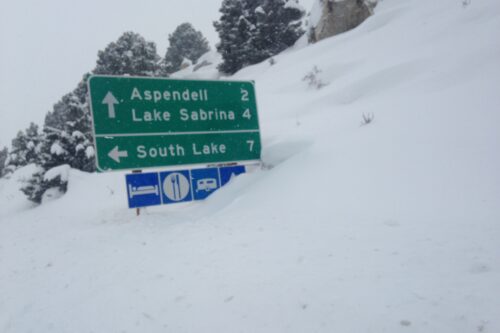 Road signs covered in snow; directions for Aspendell 2 miles, Lake Sabrina 4 miles, and South Lake 7 miles. visit bishop