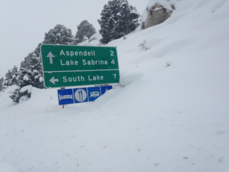 Road signs covered in snow; directions for Aspendell 2 miles, Lake Sabrina 4 miles, and South Lake 7 miles. visit bishop