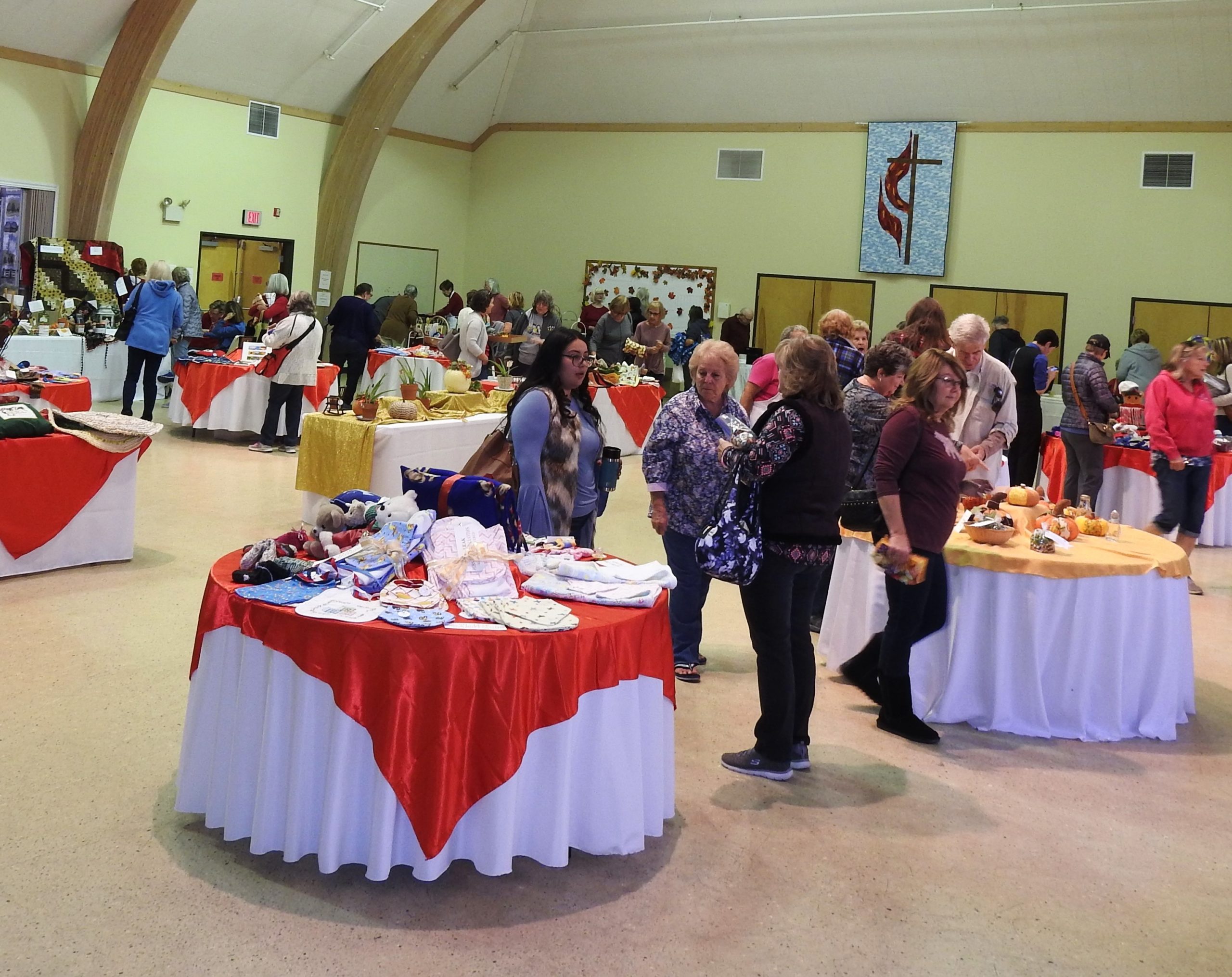 People browsing tables with various handmade items at an indoor craft fair in Bishop, California. visit bishop