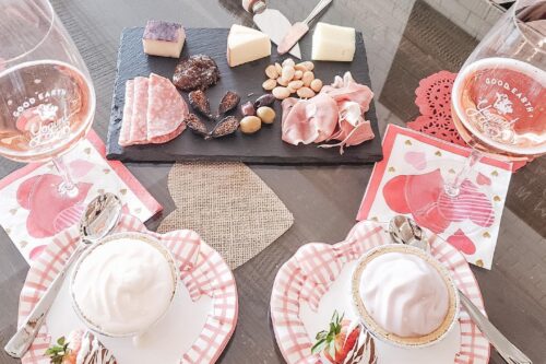 A romantic table setting with cheese, charcuterie, drinks, and desserts on heart-shaped plates and napkins. visit bishop