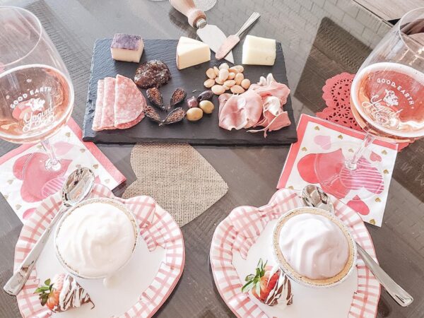 A romantic table setting with cheese, charcuterie, drinks, and desserts on heart-shaped plates and napkins. visit bishop