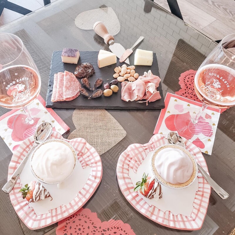 A romantic table setting with cheese, charcuterie, drinks, and desserts on heart-shaped plates and napkins. visit bishop