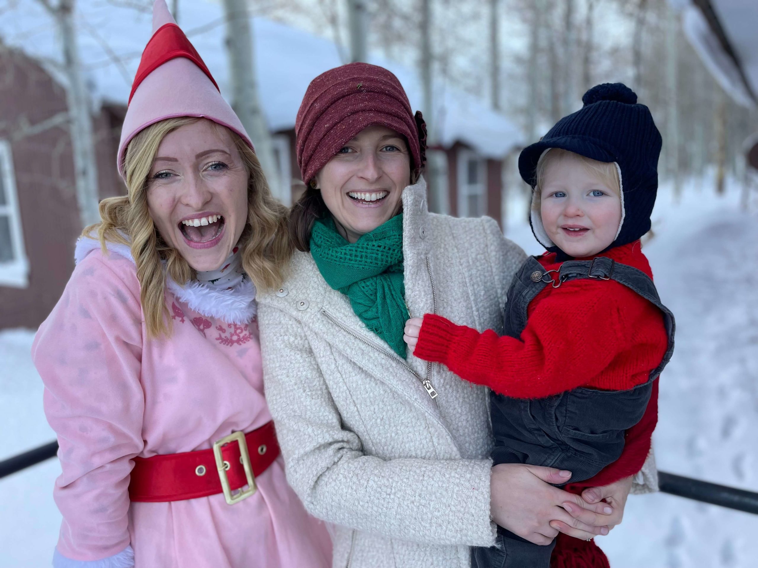 Three people bundled in winter clothes are smiling outdoors in a snowy setting, enjoying the pristine beauty of Bishop, California. visit bishop