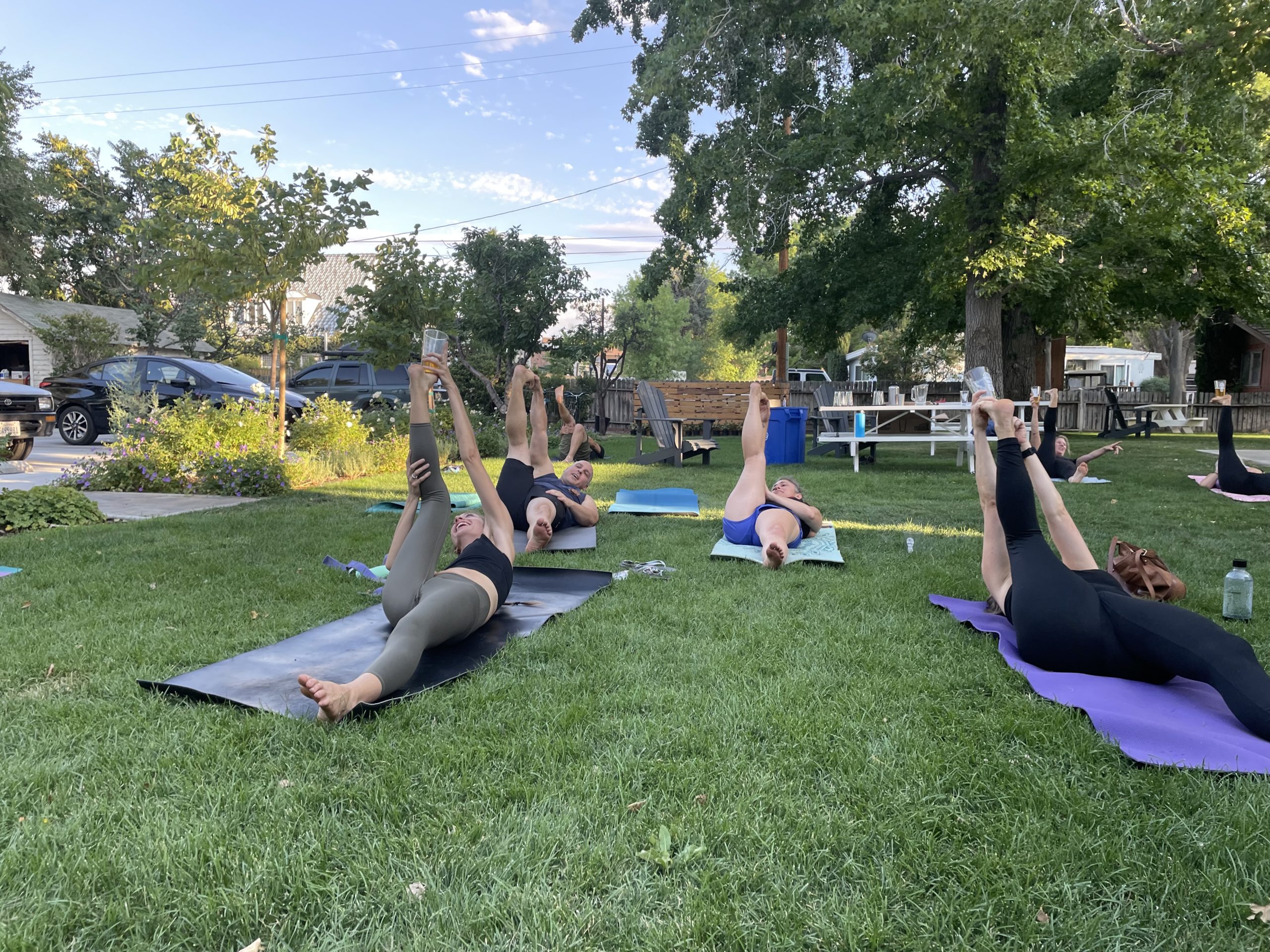 People practicing yoga on mats in a park in Bishop, California, performing leg stretches under the sunny sky of the Eastern Sierra. visit bishop