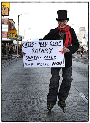 Person in a top hat and scarf roller-skating, holding a sign promoting a Rotary event to end polio, glides through the charming streets of Bishop, California. The scenic backdrop of the Eastern Sierra adds an extra touch of magic to the spirited advocacy. visit bishop