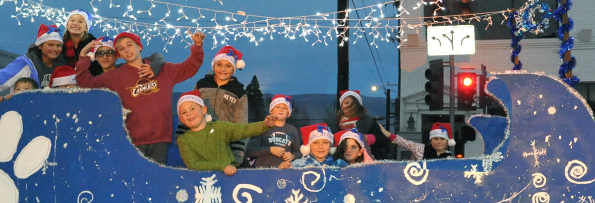 A group of children in Santa hats ride a blue sleigh float decked out with festive decorations during a holiday parade in Bishop, California, nestled in the Eastern Sierra. visit bishop
