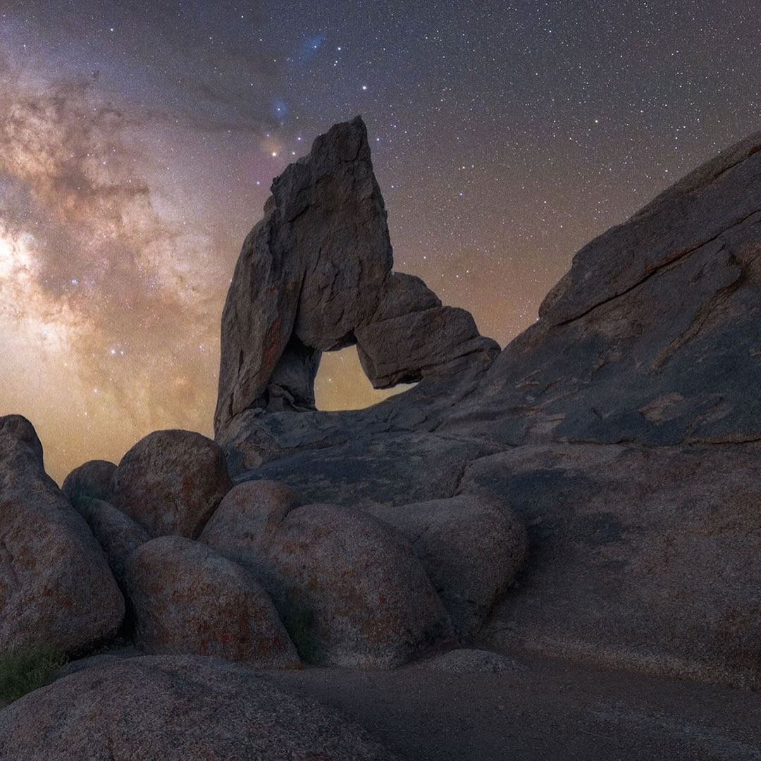 Rock formations under a starry night sky, with a large, arch-like rock in the center foreground, grace the Eastern Sierra near Bishop, California. visit bishop