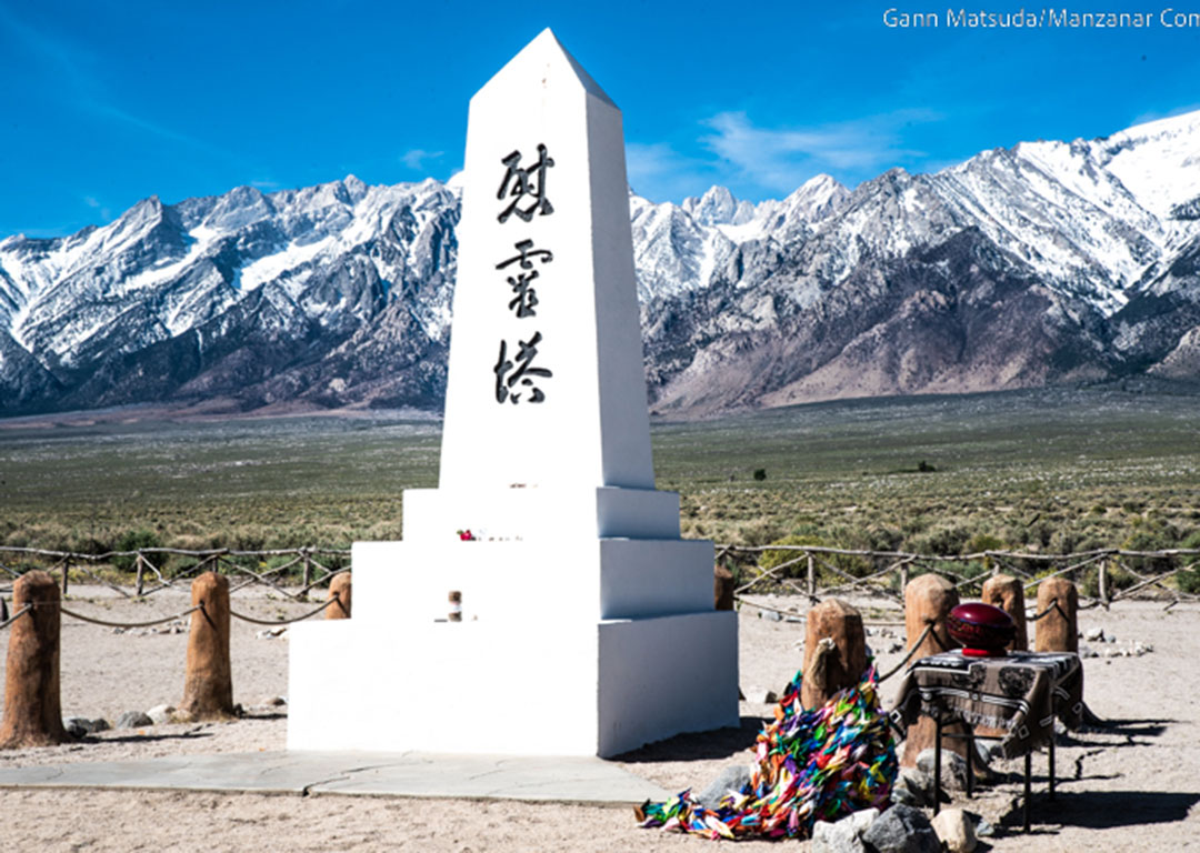 White obelisk memorial with Japanese inscription, colorful paper cranes at the base, set against the stunning backdrop of the Eastern Sierra in Bishop, California. visit bishop