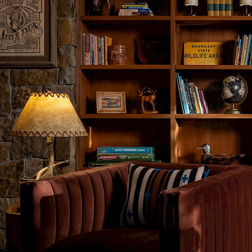 Cozy library corner with a brown sofa, bookshelves, a globe, and a lamp with a warm glow. visit bishop